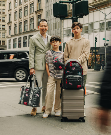 Three people with luggage on a city street