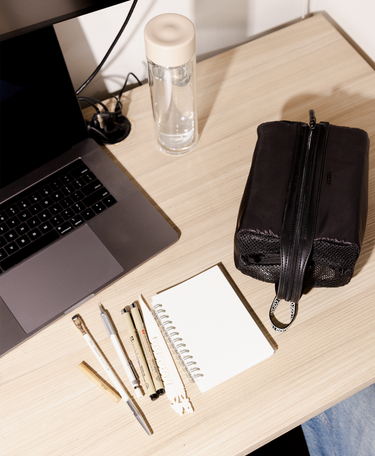 Laptop on a desk with stationery items and a water bottle