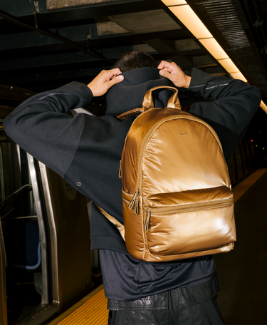 Person holding a gold backpack in an indoor setting