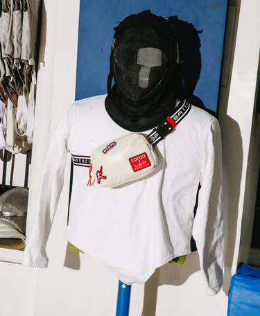 Fencing dummy wearing a black fencing mask and a white fanny pack with red and black accents.