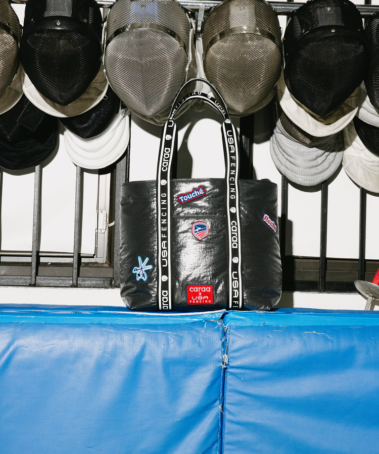 Grey tote with branding hanging on a rack with masks in the background.