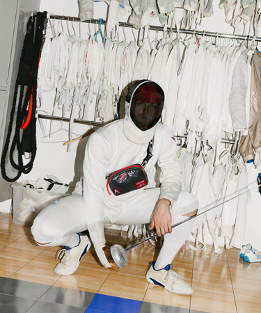 Person in fencing gear posing in front of fencing whites.