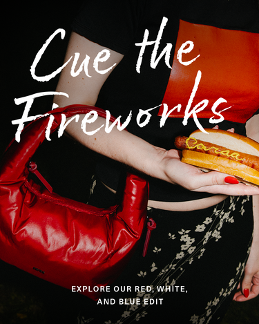 Person holding a red handbag and a hot dog with text 'Cue the Fireworks' on a black background.