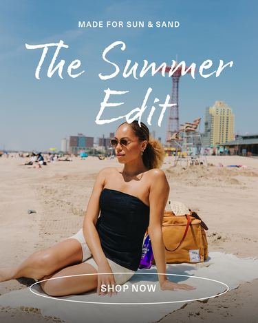 Woman sitting on a towel at the beach with text overlay 'Made for Sun & Sand, The Summer Edit, Shop Now'.