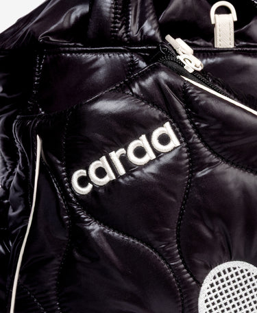 Close-up of a black quilted puffer tote with white piping and a white embroidered 'carra' logo on the front.