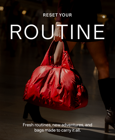 A person in a dark outfit carries a large shiny red puffer-style tote bag in a dim indoor setting. White overlaid text reads 'RESET YOUR ROUTINE' and 'Fresh routines, new adventures, and bags made to carry it all.